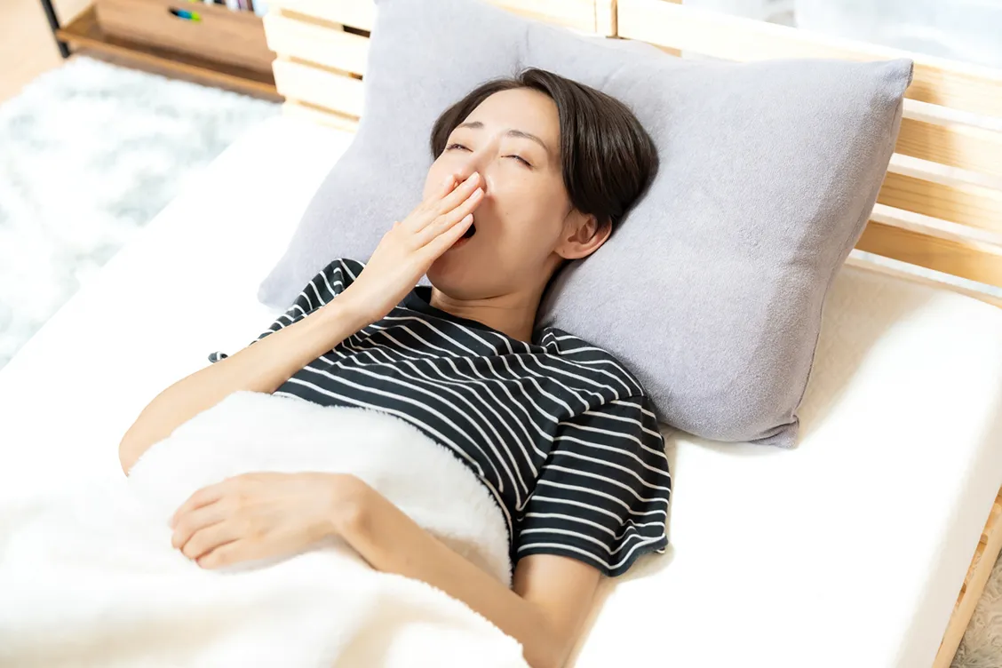 眠りが浅くあくびする女性